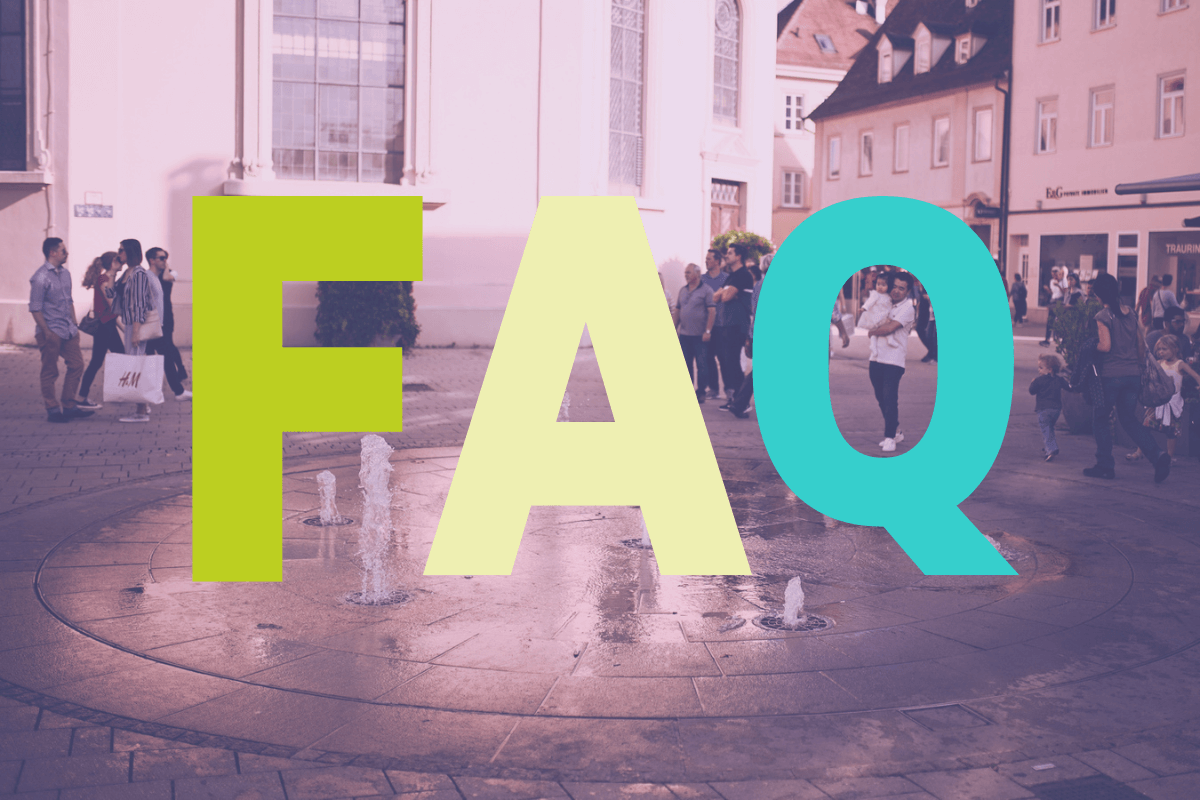 Das Bild zeigt die Asperger Straße in Ludwigsburg. Im Vordergrund befinden sich drei farbige Buchstaben: FAQ